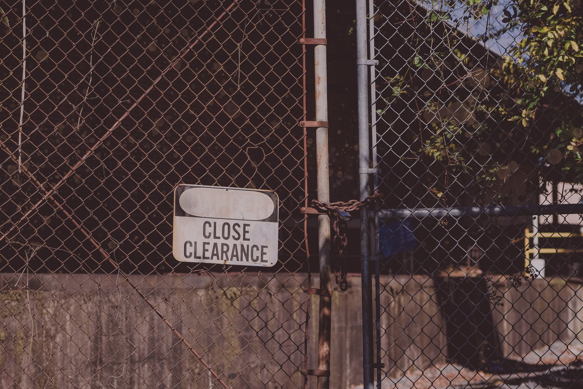 A rusty chain link fence with a 'Close Clearance' sign indicating security and safety measures in Austin, TX