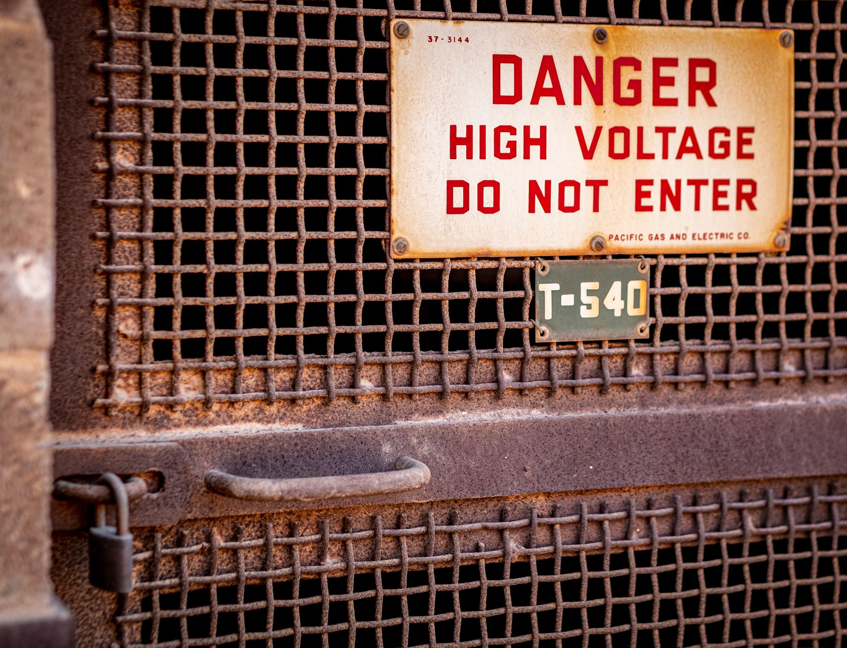 Close-up of a rusty industrial gate with a high voltage warning sign, conveying danger in Austin, TX
